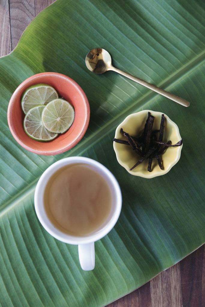 Herbal tea with lime and dried herbs served on a banana leaf